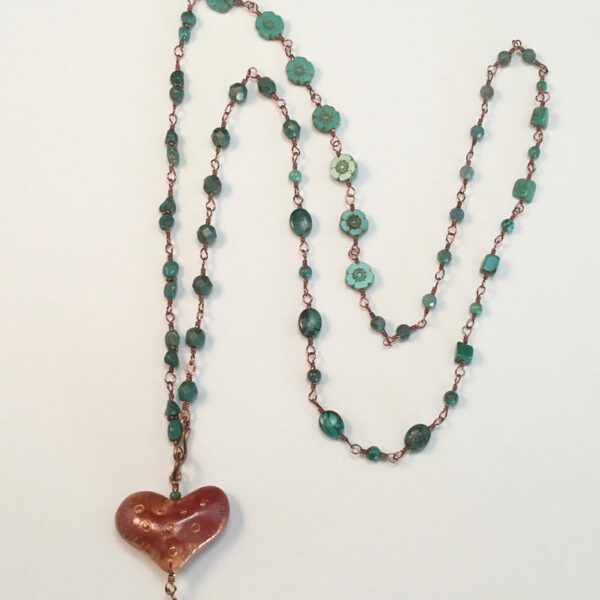 A copper heart pendant on a beaded chain