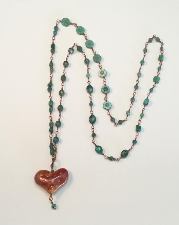 A copper heart pendant on a beaded chain