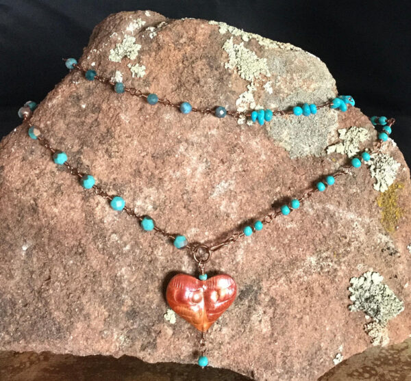 Copper heart necklace on a large rock
